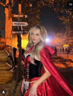 a woman in a costume standing next to a street sign