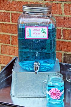 there is a glass jar with water in it on top of a metal tray next to a brick wall