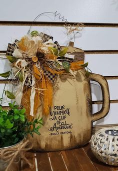 a coffee mug with a bow on it sitting next to a potted plant