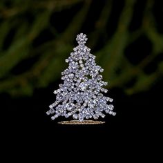 a small crystal christmas tree sitting on top of a metal stand in front of a black background