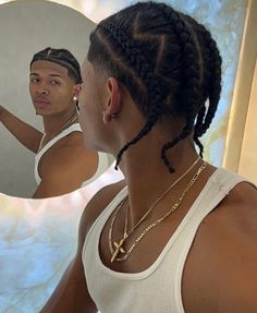 a woman looking at her reflection in the mirror while wearing a tank top and braids