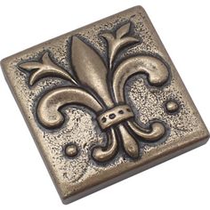 a square metal tile with fleur de lis on the front and center piece