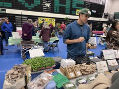 a man standing next to a table filled with lots of different types of food and plants