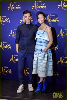 a man and woman standing next to each other on a red carpet in front of a blue backdrop