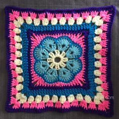 a crocheted square with pink, blue and white squares in the shape of a flower