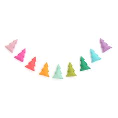 colorful felt christmas trees are lined up on a white surface