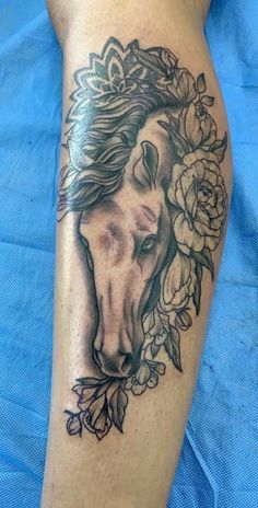 a tattoo on the leg of a person with flowers around it and a horse's head