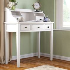 a white desk with a clock and vase on it