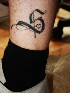 a man with a tattoo on his leg that has the letter s and is in the shape of a heart