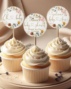 three cupcakes with white frosting and floral decorations