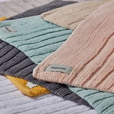 a pile of towels sitting on top of a bed next to each other in different colors