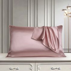 a pink pillow on top of a white dresser