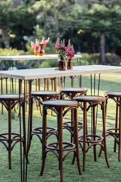 an outdoor table and chairs set up on the grass with flowers in vases above them