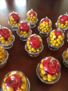 there are many small glass bowls with candies in them on the table, one is red and yellow