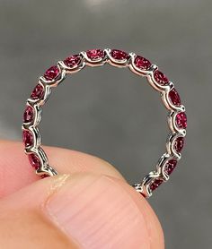 a close up of a person holding a ring with some red stones on the inside