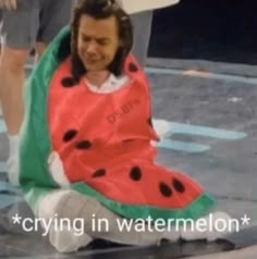 a man in a watermelon costume sitting on the ground