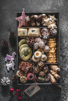 an assortment of cookies and pastries in a box on a table with christmas decorations