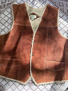 Beautiful '70s classic Western suede vest, with metal snap buttons, sherpa lining, visible stitching throughout the front, two outer pockets and the sweetest little inside pocket. ꩜Label: made in Mexico ꩜Condition: great vintage condition, gently worn. Some wear on suede on shoulder areas and a small rip on the suede near the right-side pocket. Please see close-up photos. ꩜Material: outer is genuine leather, lining is polyester (sherpa) ꩜Sizing: Fits M-L best, men's XS-S. Please check measuremen Vintage Winter Vest With Button Closure, Brown Sleeveless Vest With Faux Fur Lining, Rugged Brown Vest Outerwear, Vintage Sleeveless Winter Outerwear, Vintage Winter Vest Outerwear, Brown Rugged Vest For Winter, Brown Rugged Winter Vest, Rugged Brown Winter Vest, Vintage Leather Vest Outerwear