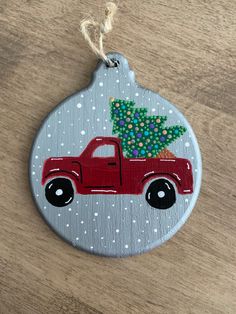 a christmas ornament with a red truck carrying a tree