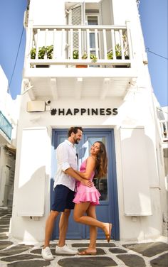 a man and woman standing in front of a blue door with the words happiness written on it