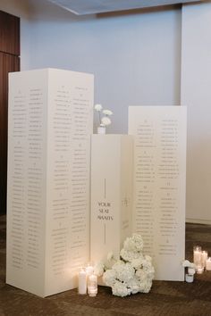 a table with flowers and candles sitting on the floor next to two tall white cards