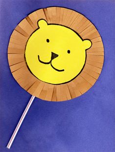 a paper plate shaped like a lion with a stick sticking out of it's face