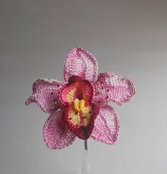 a pink crocheted flower in a glass vase