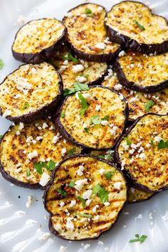 a white plate topped with cooked eggplant slices and garnished with parmesan cheese