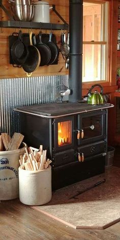 an old fashioned stove in a kitchen with pots and pans hanging on the wall