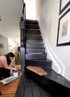 a woman kneeling down on the floor next to a stair case with wood planks