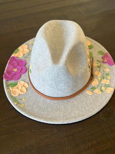 Fedora style hat with textured hand painted flowers.       -Faux leather band with gold buckle detail Material:       -65% Cotton      -35% Polyester Hat measurements:       -2.8" brim      -22.4-23.2" inner circumference      -4.7" height      -Inside circumference is fully ADJUSTABLE - there is a string pull on the inside to adjust to your perfect fit. Care Instructions:      -Spot clean only with damp cloth      -Paint can get wet and will not come off      -Do not put through the washer/dryer Hand Painted Adjustable Fedora, Hand Painted White Brimmed Hat, White Hand Painted Flat Brim Hat, Artisan Hand-painted Fedora For Festivals, Casual Hand Painted Hat, One Size Fits Most, Painted Hats, Fall Party, Hand Painted Flowers, Washer And Dryer