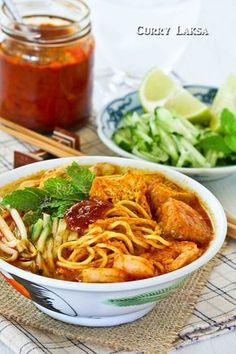 two bowls filled with noodles and vegetables next to some dipping sauce