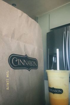 a drink in a glass next to a paper bag with the word cinnamon on it