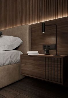 a bed sitting next to a night stand on top of a wooden floor