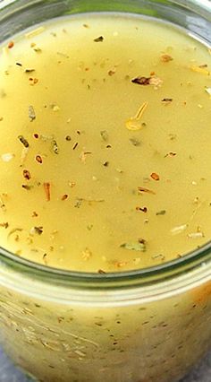 a jar filled with yellow liquid sitting on top of a table next to a spoon