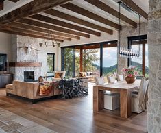 a living room filled with furniture and a fire place next to a stone wall covered in windows