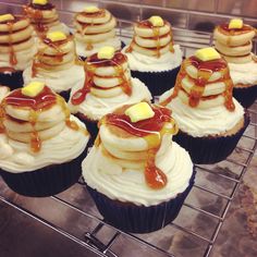 cupcakes with bananas and syrup on them sitting on a cooling rack in a kitchen