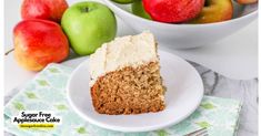 a piece of cake on a plate with apples in the background