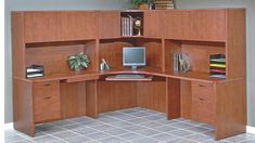 a corner desk with a computer on it in an office space that has tile flooring