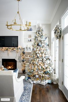 a living room decorated for christmas with a large white tree and fireplace in the corner