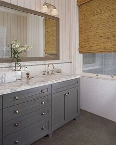 a bathroom vanity with two sinks and a large mirror above it, in front of a window