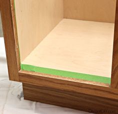 the inside of a wooden cabinet with green tape on it's edge and bottom