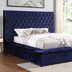 a bed with blue velvet upholstered headboard and foot board in a bedroom