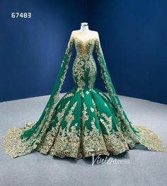 a green and gold wedding dress on display in a room with dark blue wall behind it