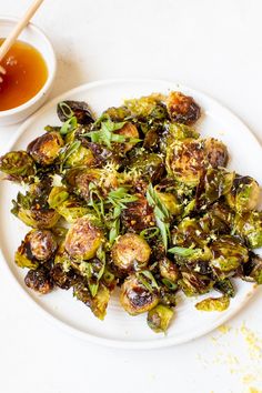 a white plate topped with brussel sprouts next to a bowl of dipping sauce