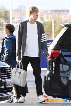 the young man is getting out of his car and holding a handbag while another person looks on