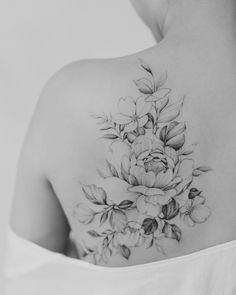 a woman's back tattoo with flowers on her left shoulder and the upper half of her body