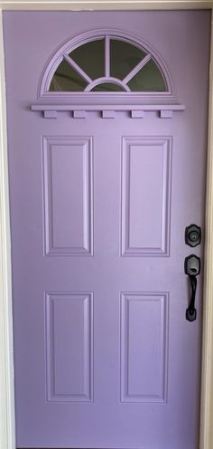 a purple front door with a phone on the side and an arched window above it