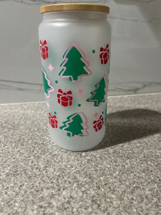 a glass jar with christmas trees and presents on it sitting on a counter next to a wall