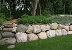 a large rock wall in the middle of a grassy area